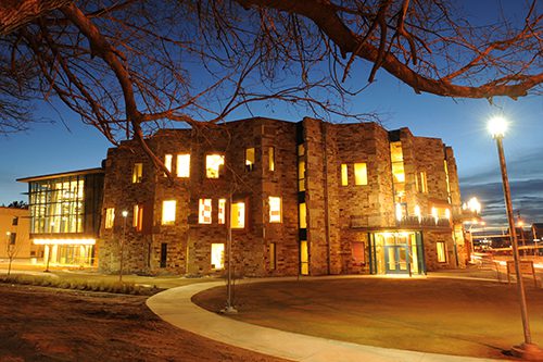 Curved stone building glowing at dusk